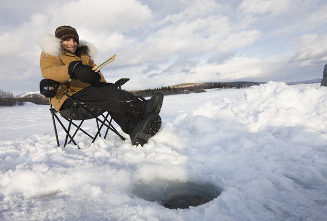Woman sits at Canadian ice hole fishing --- Image by © Robert Postma/moodboard/Corbis
